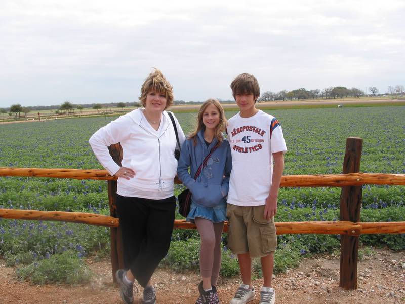 Michelle, Holly, and Andrew in front of a field of bluebonnets at Wildseed Farms