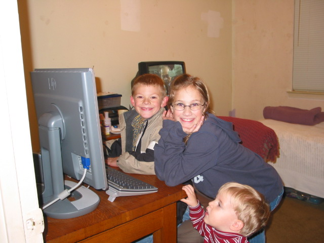 Christopher and Holly play on the computer while Jackson supervises them.