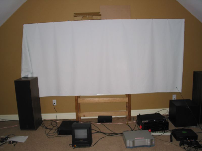 Temporary screen, blackout cloth thumb-tacked to a 10-foot 1x6 which was balanced on top of an upturned bed frame